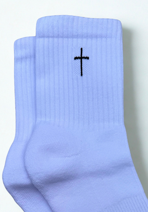 A pair of white ribbed crew socks with a small black cross on the side, shown against a plain off-white background.