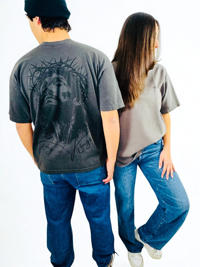 Two people wearing vintage black t-shirts with Jesus' face on the back and the cross on the front, standing back-to-back against a white background.