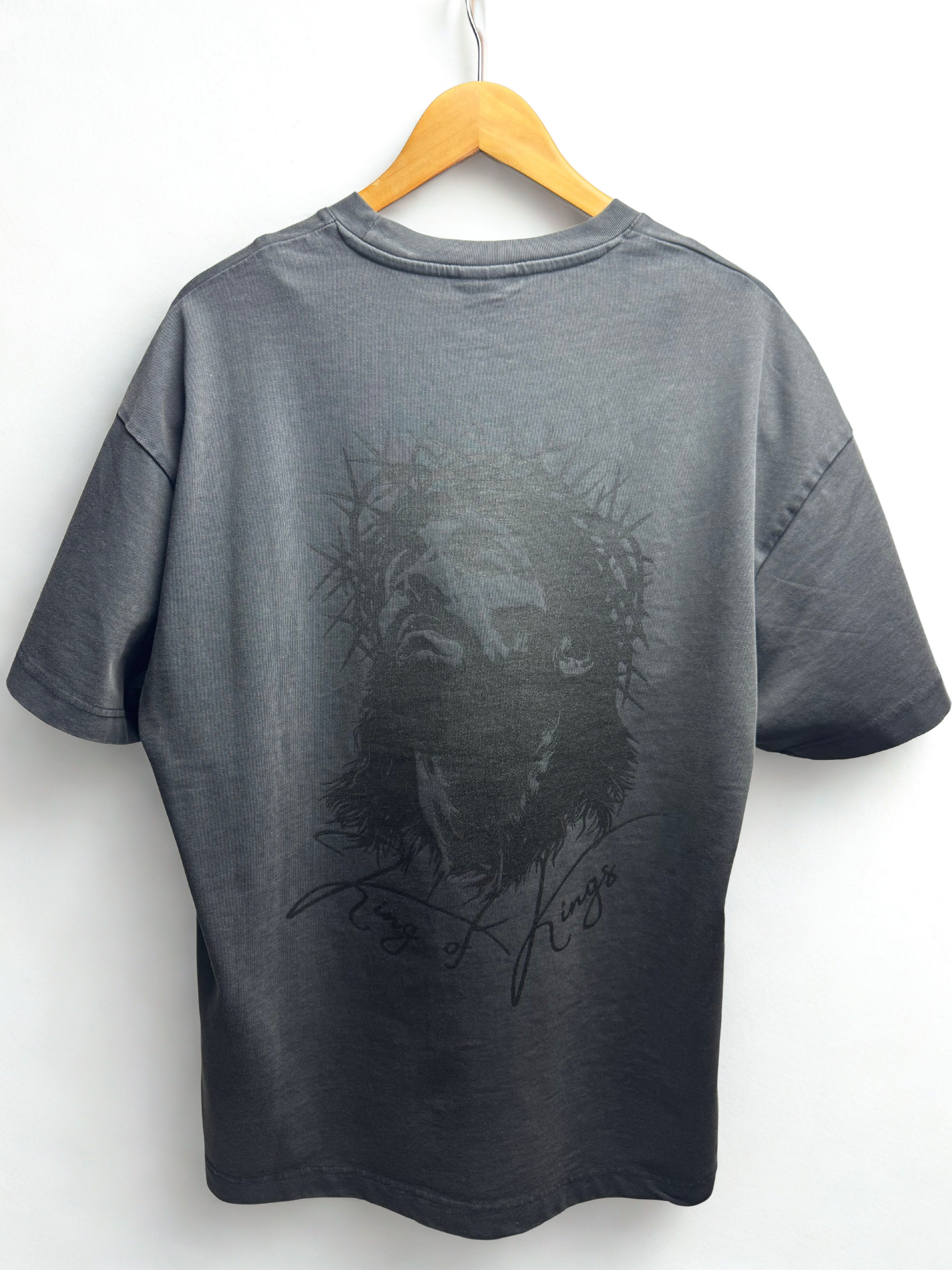 Vintage black t-shirt with Jesus' face graphic design on a hanger against a white background