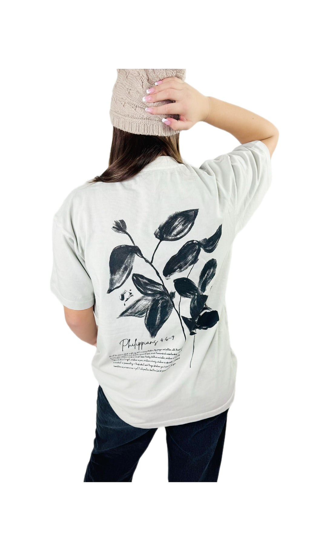 Person wearing a bone t-shirt with black leaf design and black Philippians text on a white background