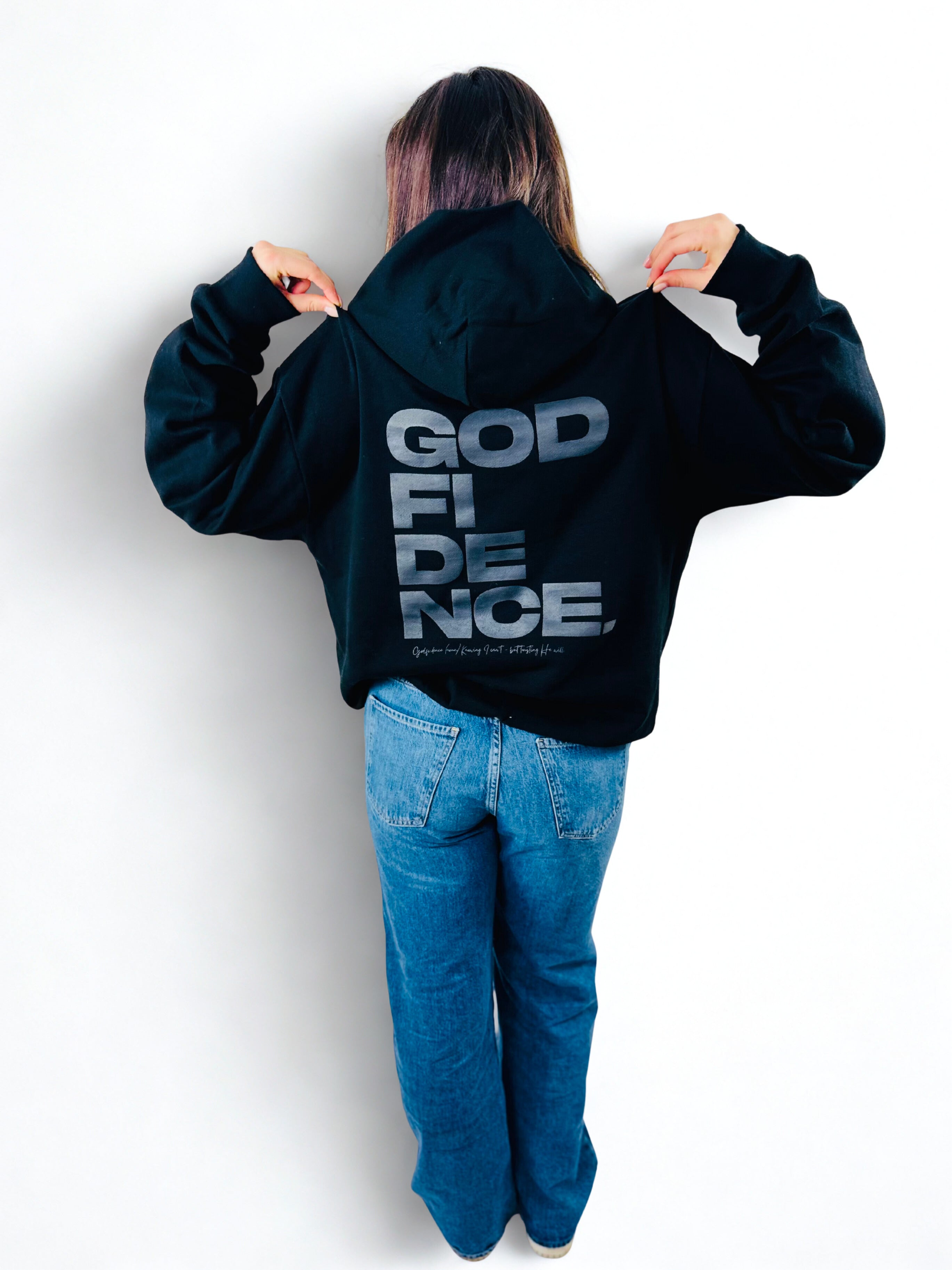 Person wearing a black hoodie with 'GOD FIDENCE' text on the back against a white background
